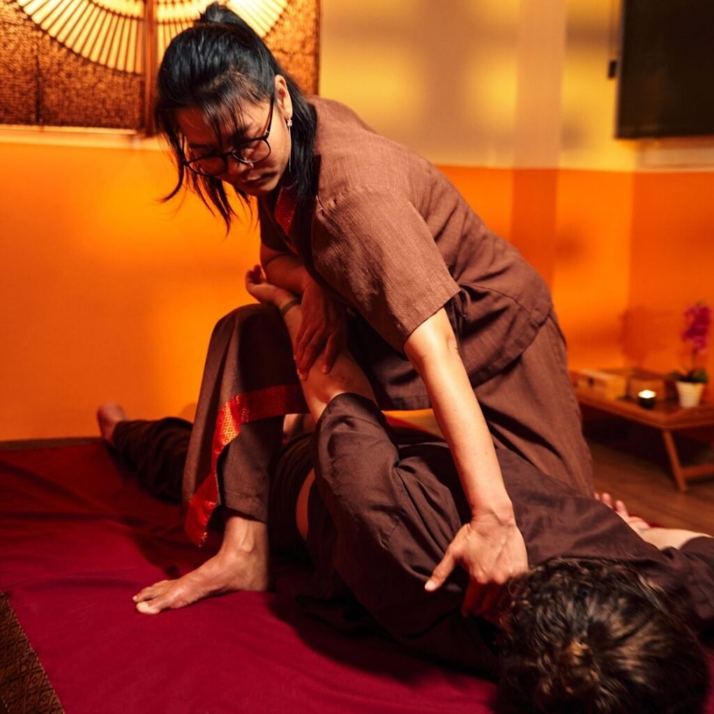 Masajista de Chiang Mai Thai Massages aplicando técnicas de masaje sobre una esterilla